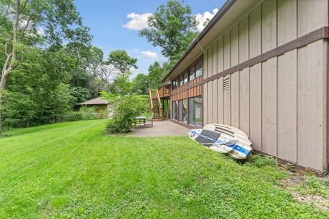 Modern building surrounded by greenery with paddleboards leaning against the wall.