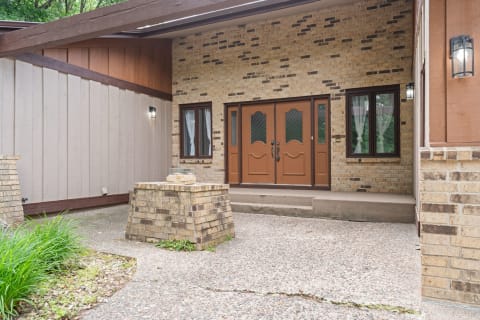 Front view of a home entrance featuring double doors and brick walls.