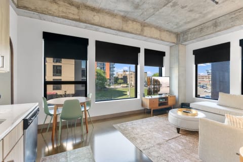 Modern living room with large windows, concrete ceiling, and minimalist furniture.