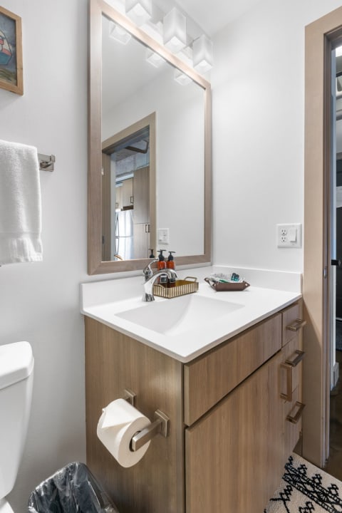 Modern bathroom with a white sink, wooden cabinetry, and stylish lighting.