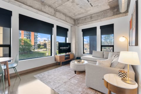 Interior view of a modern living room with a sectional couch, large windows, and a TV.
