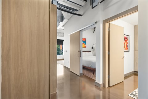 A contemporary hallway with a view into a bedroom featuring a colorful painting.
