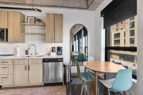 Modern kitchen with wooden cabinets, a dining table, and large windows.