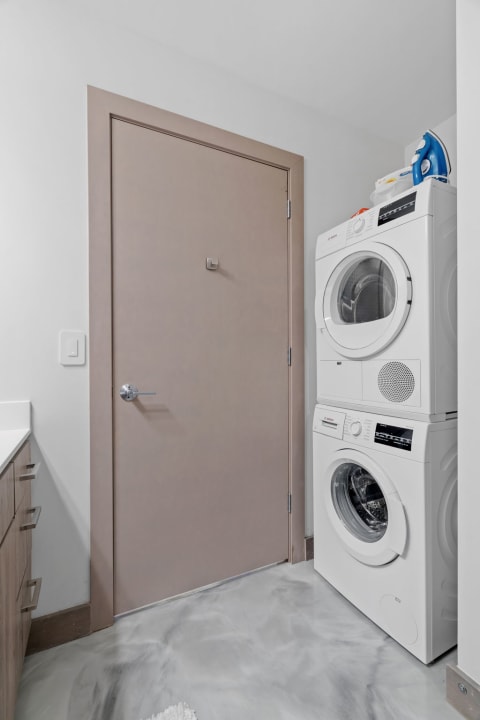 Modern laundry nook with a stackable washer and dryer against a white wall.