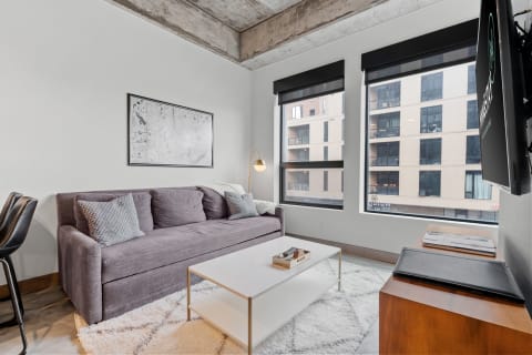 Modern living room featuring gray sofa, white coffee table, and large windows.