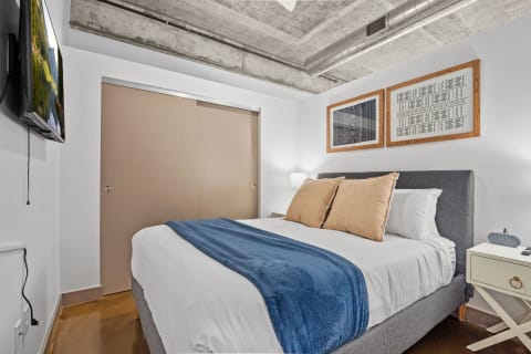 Modern bedroom with upholstered bed, decorative pillows, and artwork.