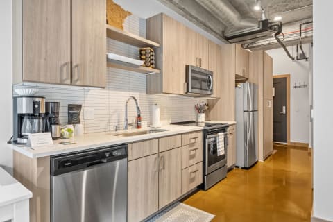 Contemporary kitchen with light wood cabinets and shiny brown floor.