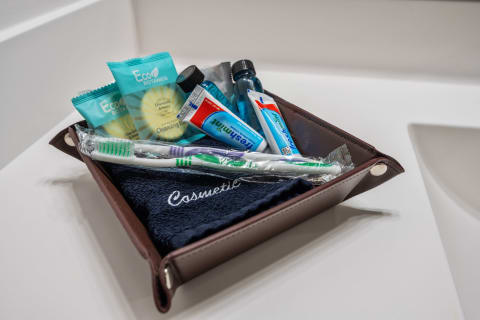An assortment of toiletries including cleansing wipes, toothpaste, and a toothbrush in a brown tray.