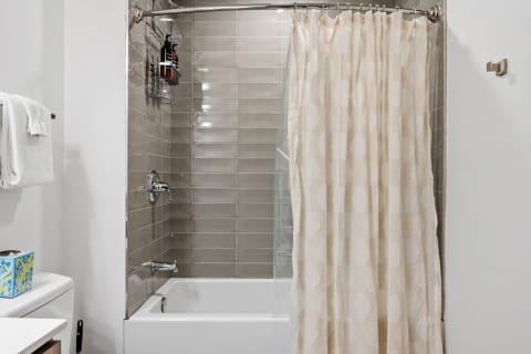 A contemporary bathroom featuring a tiled shower area and a decorative shower curtain.