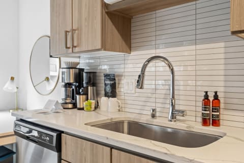 Modern kitchen with a stainless steel sink, coffee maker, and neatly arranged items.