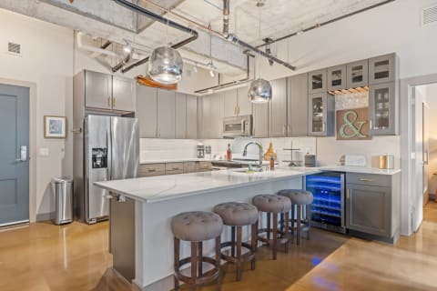 Stylish kitchen featuring gray cabinets, a white island countertop, and stainless steel appliances.