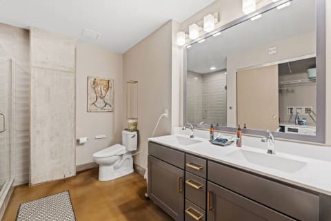 A contemporary bathroom with a walk-in shower, dual sink vanity, and artistic decoration on the wall.