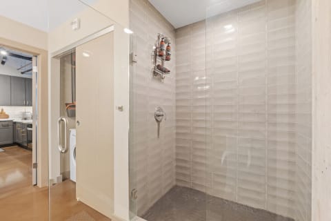 Modern shower area with glass enclosure and hexagonal tiled floor.