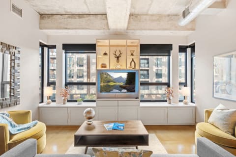 Contemporary living room with exposed concrete beams, a yellow sofa, a gray sofa, a coffee table, and an entertainment unit.