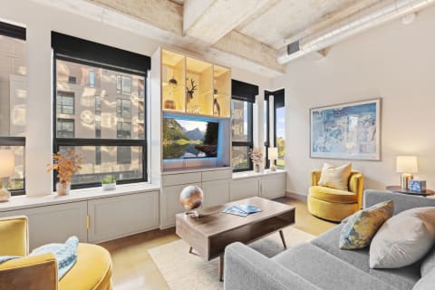 Contemporary living room featuring gray sectional, yellow chair, and wall-mounted TV.