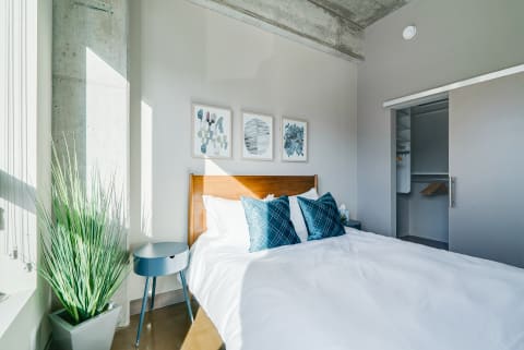 Cozy modern bedroom with a wooden bed, teal pillows, and abstract art on the walls.