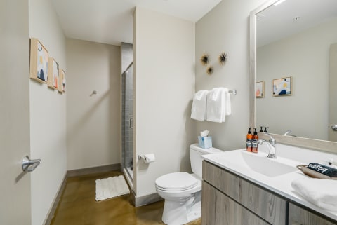 Modern bathroom featuring white towels, a glass shower, and abstract art on the walls.