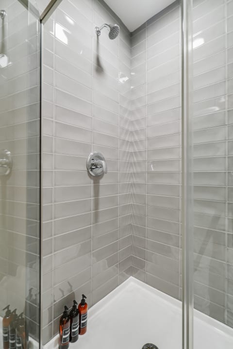 Contemporary shower with gray wall tiles and organizing toiletries.
