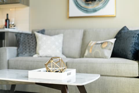 Modern living room with a grey sofa and a geometric gold sculpture on a coffee table.