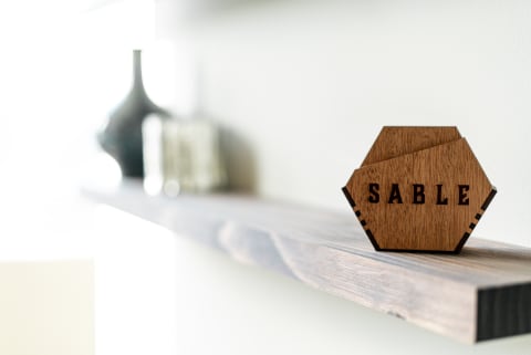Geometric wooden piece with the word 'SABLE' on a shelf.