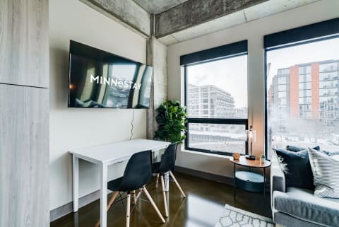 Modern living space with a desk, TV, and large windows.