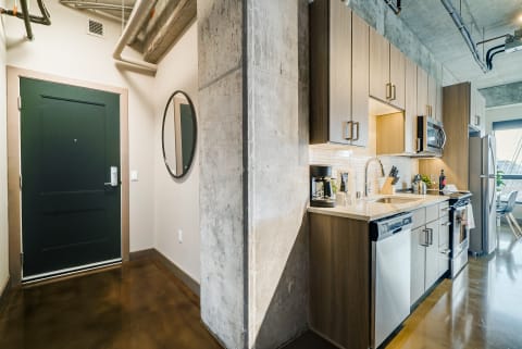 Modern kitchen with a dark green door and polished concrete floor.