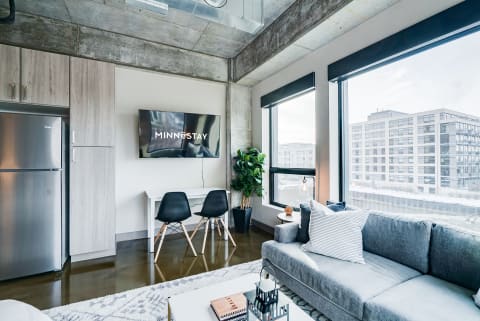 Contemporary apartment living space featuring a sofa, desk, and large windows.