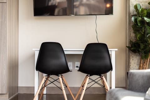 Modern workspace with two black chairs facing a white desk under a television.