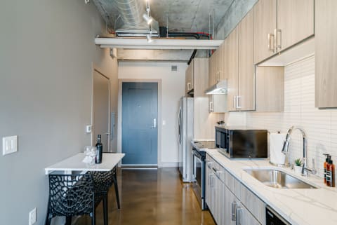 Contemporary apartment kitchen with wood cabinets and a small dining area.