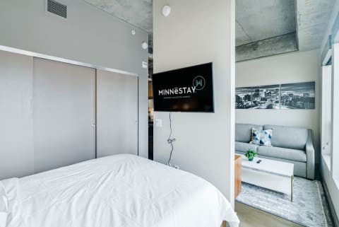 Interior view of a contemporary studio apartment featuring a bed, sofa, and wall-mounted TV.