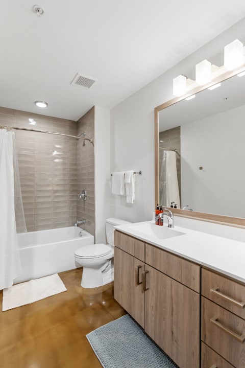 A contemporary bathroom featuring a bathtub, wooden vanity, and stylish lighting.