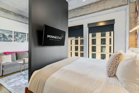 Interior view of a modern vacation home with a bed, sofa, and large windows.