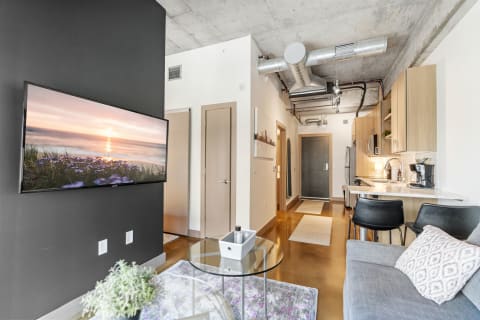 Interior view of a modern apartment with a living area, kitchen, and entrance.