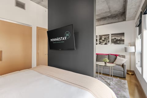 Interior view of a rental space featuring a bed, TV, and seating area.