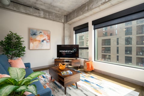Modern living room featuring a blue sofa, colorful rug, and flat-screen TV.