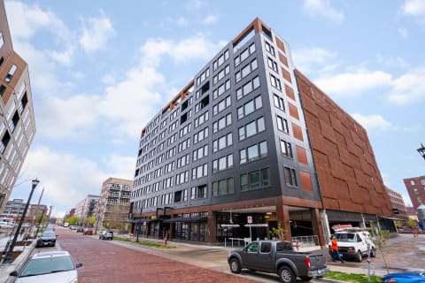 A contemporary multi-story building with large windows and retail spaces on the ground floor.