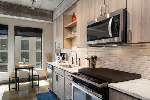 Modern kitchen featuring stainless steel appliances, a marble countertop, and a small dining area with two benches.