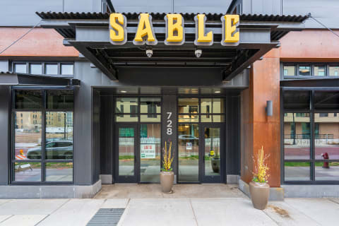 Modern building entrance with the name SABLE and decorative flower pot.