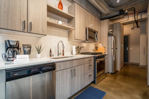 Modern kitchen with wooden cabinets, stainless steel appliances, and a polished concrete floor.