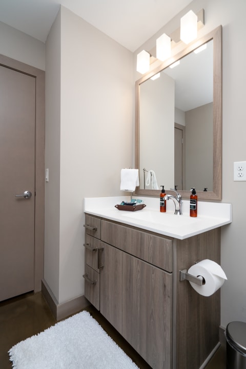 Modern bathroom featuring a light wood vanity, white countertop, and elegant lighting.