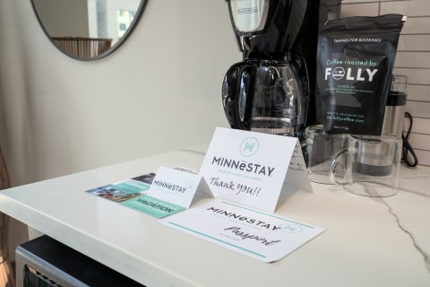 A countertop with a coffee maker, coffee pack, and MINNESTAY promotional cards.