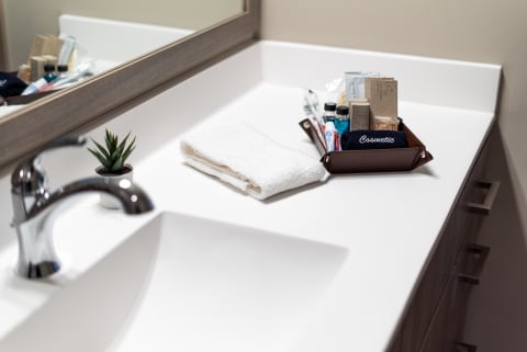 Bathroom countertop with a chrome faucet, towel, and cosmetic items in a tray.