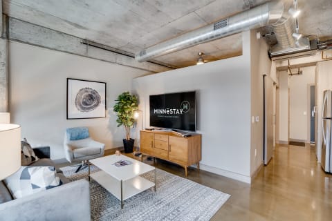 A stylish living room featuring a gray sofa, modern artwork, and a flat-screen TV in a contemporary apartment.