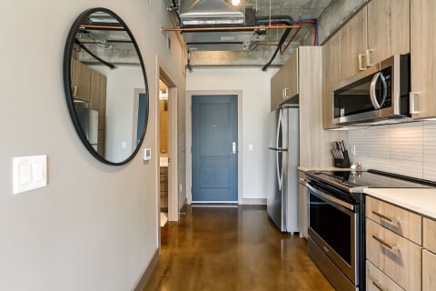 A contemporary kitchen with polished concrete floor, stainless steel appliances, and a black mirror.