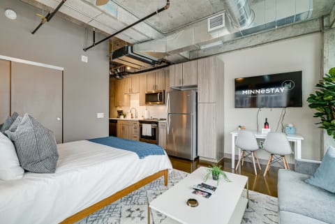 Modern studio apartment with a bed, kitchen, and dining area.