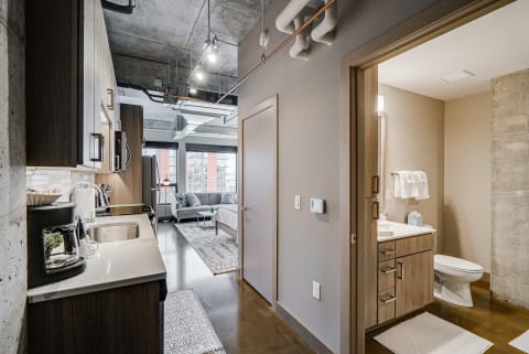 Interior of a contemporary apartment featuring a kitchen, living area, and bathroom.