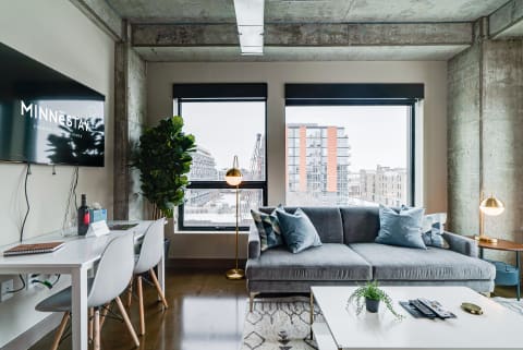 Contemporary living room featuring a grey sectional couch, a coffee table, and large windows with a city view.