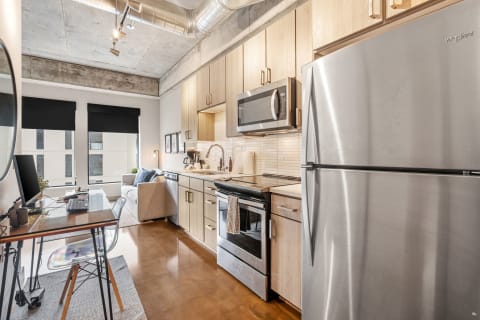 Interior view of a modern kitchen-living area with stainless steel appliances and minimalist furniture.