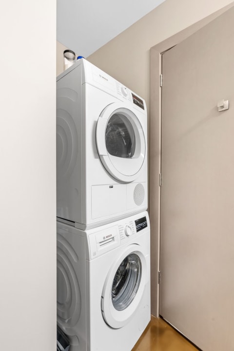 A white Bosch stacked washer and dryer in a small laundry corner.