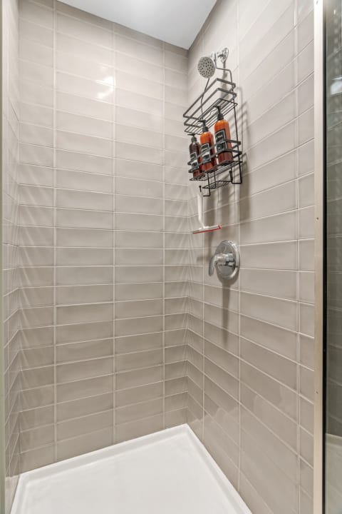 Interior view of a modern shower with light beige tiles and a chrome faucet.
